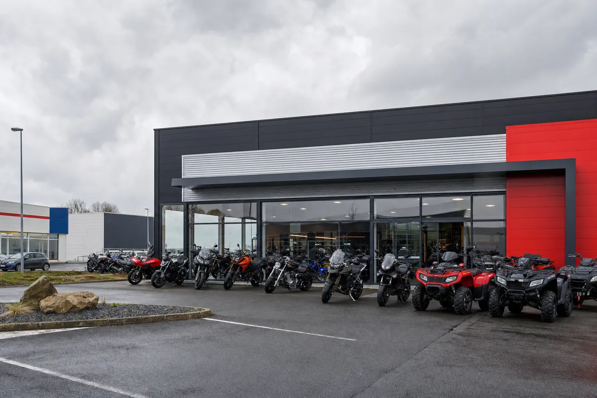 Vitrine extérieure d’une concession moto et quad dans une zone commerciale, ciel nuageux